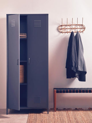A CHOICEWARDROBE Ruston Grey Metal Locker Wardrobe with two doors, shelves, and hanging rail stands next to a wooden bench in the entryway. A wall rack with two dark coats and a rug are also visible in the scene.