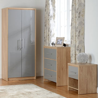The CHOICEWARDROBE Samaira 2 Door Wardrobe in grey gloss with an oak effect frame adds a modern touch to the bedroom, pairing perfectly with a three-drawer chest, bedside table, light curtains, and a white rug for a complete contemporary look.