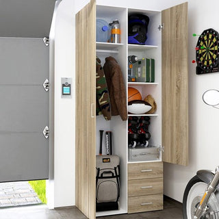 The CHOICEWARDROBE Scalia 2 Door 3 Drawer Wardrobe in Modern Oak Finish (77cm wide) stands open, its shelves neatly storing sports gear, a helmet, camo jacket, books, boxes, and a backpack. A dartboard and bicycle are nearby beside the open garage door.