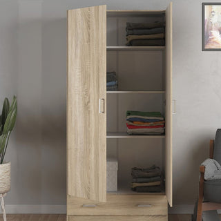 The CHOICEWARDROBE Scalia Oak 3 Piece Bedroom Set features a 2 door wardrobe, shown open with folded clothes on three shelves and a white box below. A plant, part of a chair, and wall art are nearby. Natural light oak finish with silver handles.