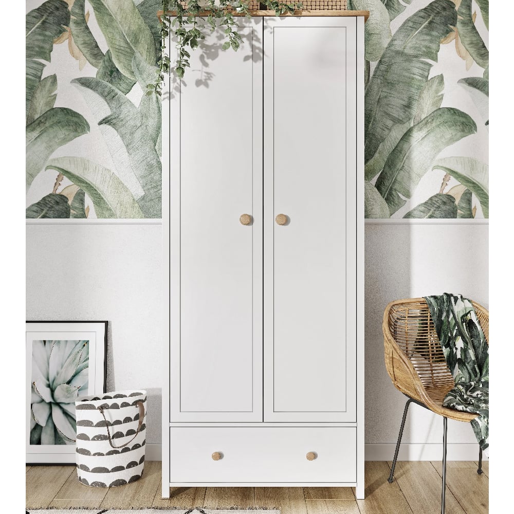 White 2 door wardrobe with drawer, set against leaf-patterned wallpaper and styled with a rattan chair.