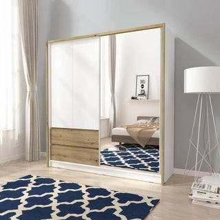 A modern bedroom features the CHOICEWARDROBE Soren 204cm 2 Door Sliding Wardrobe with an Oak Artisan frame, mirror, and white panels. In its reflection, a bed, blue-and-white patterned rug, and floor lamp are visible.
