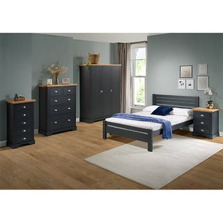 A bedroom with blue-green walls, wooden floors, a bed with a blue-gray frame and white bedding, matching nightstand, dresser, chest, and a CHOICEWARDROBE Talox 3 Door Wardrobe in grey with an oak top. A white rug lies under the bed.