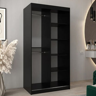 The CHOICEWARDROBE Tavira 100cm Black Mirrored Sliding Door Wardrobe features a modern compact design with a hanging rail and storage shelves, shown in a stylish room with vertical wall accents and chic decor.