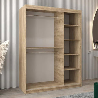 The CHOICEWARDROBE Tavira 150cm Sonoma Oak Mirrored Sliding Door Wardrobe, featuring a compact 2-door design with full-length mirrors and a natural wood finish, stands against a striped wall in a modern room.