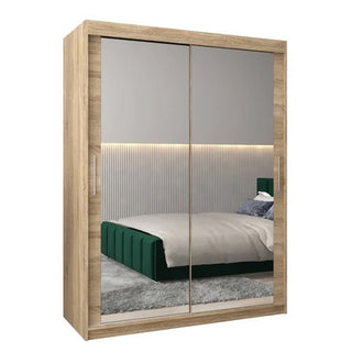 The CHOICEWARDROBE Tavira 150cm Sonoma Oak Mirrored Sliding Door Wardrobe adds modern style to the bedroom, complementing a green upholstered bed, gray carpet, and vertical paneling with LED strip lighting.