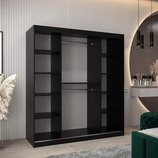 The CHOICEWARDROBE Tavira 180cm Black Sliding Door Wardrobe, featuring a sleek modern design with hanging rail and adjustable shelves, stands against a striped wall in a neutral contemporary room with a round lighted mirror.