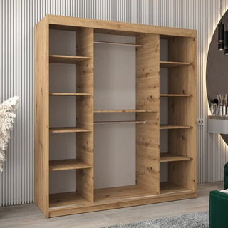The CHOICEWARDROBE Tavira 2 Door Oak Effect Sliding Wardrobe (180cm) with shelves, a hanging rail, and mirrored doors stands against vertical white paneling. A mirror and vanity appear on the right side of the image.