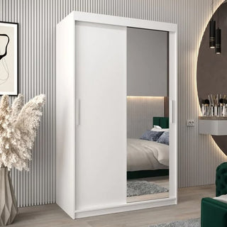 A modern bedroom featuring the CHOICEWARDROBE Tavira 2 Door Sliding Mirrored Wardrobe in white, a bed, pampas grass vase, wall art, and a mirrored vanity blends style with smart storage solutions.