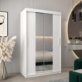 The CHOICEWARDROBE Tavira 2 Door Sliding Mirrored Wardrobe in white features a modern full-length mirror, shelving, and hanging rail (120cm), offering stylish storage beside a pampas grass vase and round wall mirror in the bedroom.