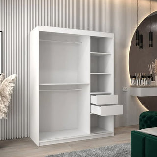 The CHOICEWARDROBE Tavira 2 Door Sliding Wardrobe in a 150cm matt white finish features shelves and drawers, blending style and function in a modern room with vertical panels, a round mirror, and décor on the nearby vanity.