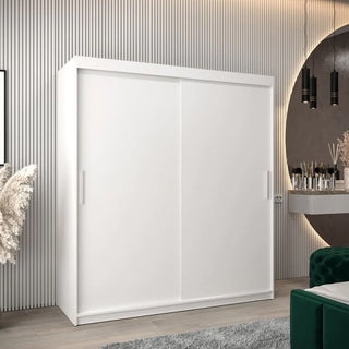 The CHOICEWARDROBE Tavira 2 Door Sliding Wardrobe (180cm, Matt White) with minimalist modern design and spacious shelving stands by a wall. A nearby vanity table, round mirror, and plant enhance the room’s contemporary look.