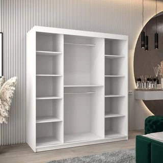 The CHOICEWARDROBE Tavira 2 Door Sliding Wardrobe in 180cm Matt White, featuring a minimalist modern design with spacious shelving and rails, stands against a wall. Decorative items and a vanity area appear on the right.
