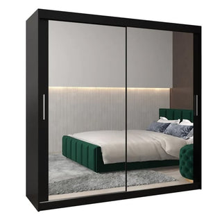 The CHOICEWARDROBE Tavira 250cm Sonoma Oak Mirrored Sliding Door Wardrobe with a modern 3-door design and full-length mirrors enhances a bedroom with a green upholstered bed, gray rug, and vertical paneling with LED strip lighting.