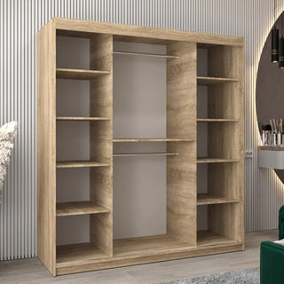 A CHOICEWARDROBE Tavira 3 Door Sliding Mirrored Wardrobe in Sonoma Oak finish with full-length mirror panels, hanging rail, and organised shelves stands against a grooved wall. A green chair and small vanity are partially visible on the right.