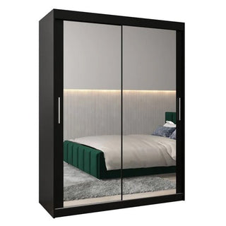 A CHOICEWARDROBE Tavira III Mirrored Wardrobe with 2 sliding doors (150cm, black) features full-length mirrors and storage shelves, reflecting a modern bedroom with a green bed, gray rug, pillows, and wall lighting behind the bed.