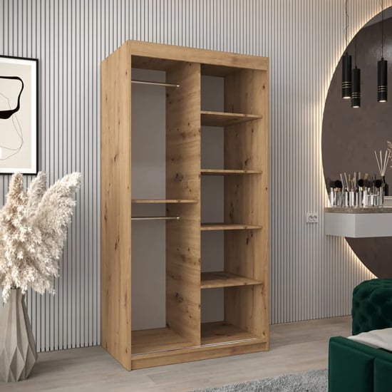 Open wooden wardrobe with natural Artisan Oak finish, showing internal shelves and a hanging rail. Sliding doors evident.