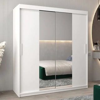 The CHOICEWARDROBE Tavira White Mirrored Sliding Wardrobe (180cm, 2 doors) features in a modern bedroom with vertical wall paneling. Its mirrored doors reflect the bed and lighting, creating a bright, spacious atmosphere.