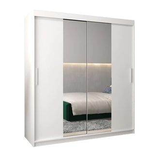 The CHOICEWARDROBE Tavira White Mirrored Sliding Wardrobe (180cm, 2 doors) reflects a neatly made bed, rug, and softly lit wall, while offering spacious storage with shelves, drawers, and a hanging rail.