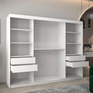 The CHOICEWARDROBE Tavira White Mirrored Sliding Wardrobe (250cm, 3 doors) with a full-length mirror, shelves, and hanging rails offers stylish bedroom storage against a textured wall near a vanity on a light-colored floor.