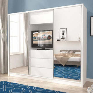 A modern bedroom features the CHOICEWARDROBE Telluride 254cm 2 Door Sliding Mirrored Wardrobe in white gloss with central storage drawers, reflecting a tidy bed, blue circular rug, curtained window, and a TV displaying a race car.