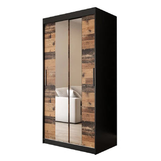 The CHOICEWARDROBE Topeka 100cm Dark Oak & Black Sliding Mirrored Wardrobe adds modern industrial style, with two mirrored doors reflecting a white sofa and beige wall, and a rustic wood panel design for contemporary bedrooms.