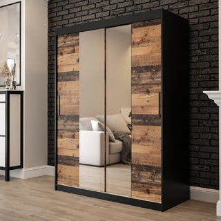 The CHOICEWARDROBE Topeka 2 Door Sliding Mirrored Wardrobe in rustic oak and black stands by a black brick wall, its mirrored doors reflecting a white couch and pillows, adding industrial-modern flair with built-in hanging rail and shelves.