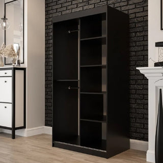 The CHOICEWARDROBE Topeka Dark Oak 2 Door Sliding Mirrored Wardrobe stands against a black brick wall, providing contemporary bedroom storage. The room has light wood floors with white and black furniture accents.