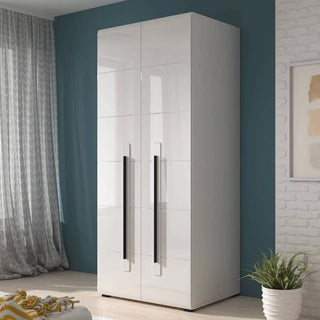The CHOICEWARDROBE Trail 90cm White High Gloss 2 Door Wardrobe, featuring tall handles, adds sleek modern style to a bedroom with teal walls, sheer gray curtains, a white brick accent wall, and a nearby potted plant.