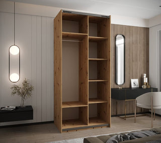 The CHOICEWARDROBE Tressaro Artisan Oak Sliding Wardrobe (2 Door with Mirror, 100cm) adds rustic elegance to a modern bedroom with a desk, chair, round mirror, wall-mounted lights, and light-dark wood paneling.