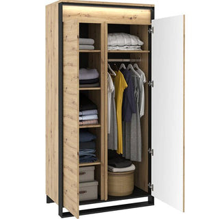 The CHOICEWARDROBE Varen 95cm 2 Door Wardrobe in artisan oak with a black frame features shelves, a hanging rod, basket, and storage boxes. Built-in LED lighting highlights the organized interior visible through partially open doors.
