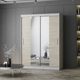 The CHOICEWARDROBE Vetra 2 Door Sliding Mirror Wardrobe (150cm, Sonoma Oak with White Trim, shelves & hanging rail) stands against a gray wall; in front is a round table with a vase, and built-in shelves with lights add style on the right.