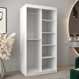 The CHOICEWARDROBE Vevey 100cm White Mirrored Sliding Door Wardrobe with a modern panel design, full-length mirror, two hanging rods, and four open shelves stands on a light wood floor against a vertically grooved wall.