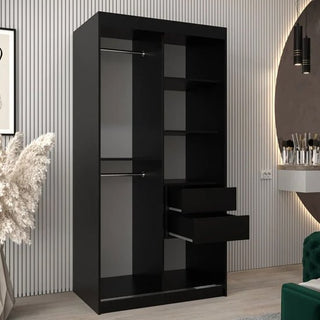 The CHOICEWARDROBE Vevey 2 Door Sliding Wardrobe in a 100cm black finish with chrome detailing stands in a modern room with striped walls, plants, and a round mirror. Some drawers are partially open, showing its handy shelving and hanging rail.