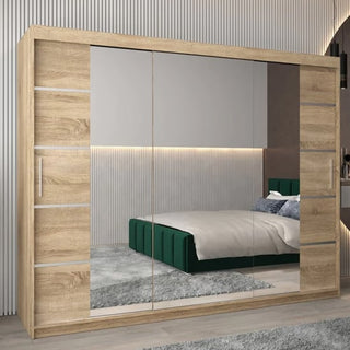 The CHOICEWARDROBE Vevey 250cm 3 Door Sliding Mirrored Wardrobe in Sonoma Oak stands in a modern bedroom, its mirrored doors reflecting a green bed with pillows and a wall featuring horizontal strip lighting.