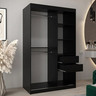 The CHOICEWARDROBE Vevey Black Mirrored Sliding Wardrobe (120cm, 2 doors) with a modern high-gloss finish, shelves, rails, and a full-length mirror offers stylish bedroom storage in a contemporary room with decor arranged around it.