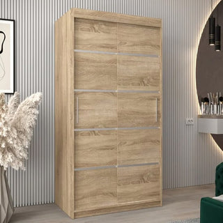The CHOICEWARDROBE Vevey I 2 Door Sliding Wardrobe in Sonoma Oak stands against a striped wall in a modern room, with a framed picture, pampas grass arrangement, and vanity table nearby.