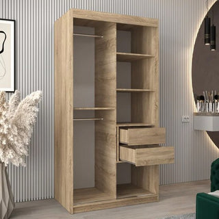 The CHOICEWARDROBE Vevey I 2 Door Sliding Wardrobe in Sonoma Oak finish, featuring shelves and a hanging rail (100cm wide), stands against a light-striped wall in a modern room with plants and a mirror nearby.