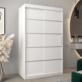 The CHOICEWARDROBE Vevey I Wooden Wardrobe—2 sliding doors in white, 120cm with shelves and smooth glide panels—stands against a grooved wall, complemented by artwork, a vase with pampas grass, and a vanity for contemporary decor.