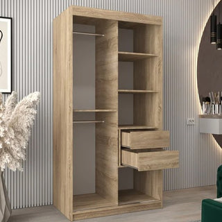 The Eden Mirrored Wardrobe 2 Sliding Doors 100cm in Sonoma Oak features open shelves, two hanging rods, and two partially open drawers. It stands against a vertically grooved wall with nearby decorative items and furniture.