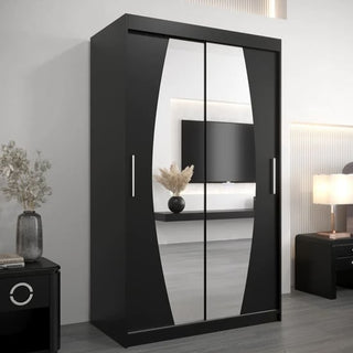 The Eden Mirrored Wardrobe 2 Sliding Doors 120cm in Black, featuring a geometric design and silver handles, stands in a minimalist room with a lamp, TV, and decorative vase.