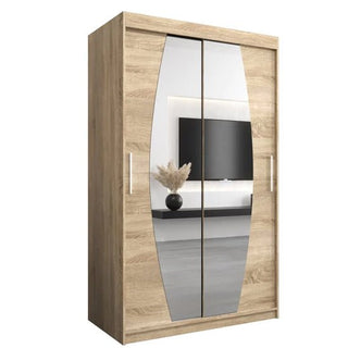 The Eden Mirrored Wardrobe 2 Sliding Doors 120cm in Sonoma Oak features mirrored sliding doors with vertical handles. Reflections in the mirrors show a vase with dried plants and a wall-mounted TV.