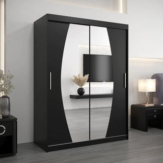 The Eden Mirrored Wardrobe 2 Sliding Doors 150cm in Black, featuring curved-edge mirrors, stands in a bedroom and reflects a TV, floating shelf with a vase, lamp, and nightstands for a stylish decor touch.