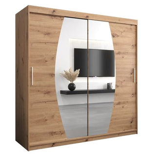The Eden Mirrored Wardrobe 2 Sliding Doors 200cm in Artisan Oak features sliding doors and a large, vertically oval-shaped center mirror, reflecting a mounted TV, wall shelf, and vase with dried plants for added charm.