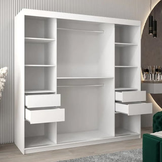 The Eden Mirrored Wardrobe 2 Sliding Doors 200cm in White, featuring shelves, two hanging rods, and four open drawers, stands against a ribbed wall in a modern room with a green chair and vanity table.