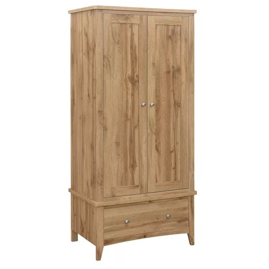 Oak finish wooden wardrobe with 2 doors and 1 drawer, featuring metal handles and standing on short legs.