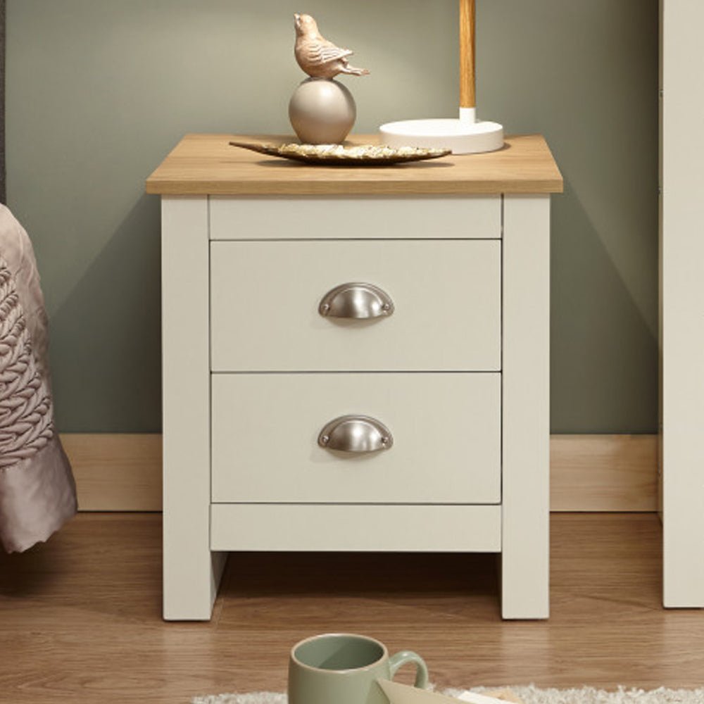 Cream and oak bedside cabinet with two drawers and silver cup handles.