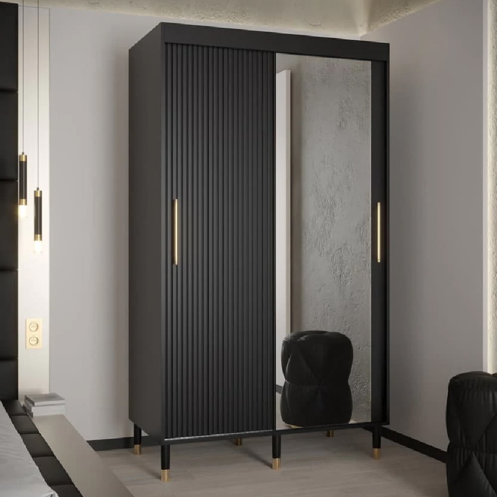 Black wardrobe with 2 sliding doors, one ribbed, one mirrored, gold handles and legs.