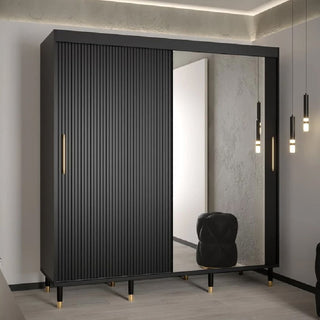 The Millwall 200cm Mirrored Wardrobe With 2 Sliding Doors in Black features gold handles and legs, one vertically grooved door, and one mirrored door—ideal for compact bedrooms. It comes with a black cushioned stool and pendant ceiling lights.
