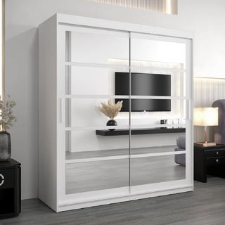 The Reston Mirrored Wardrobe With 2 Sliding Doors In White stands in a modern room, reflecting a wall-mounted TV, a floating shelf, and a decorative vase filled with dried grass.